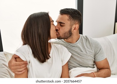 Young Latin Couple Kissing And Hugging On The Bed At Home.