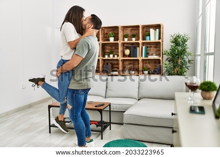 Young latin couple kissing and hugging at home.