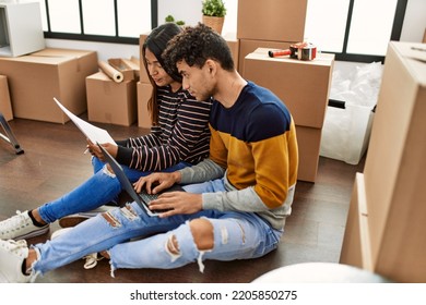 Young Latin Couple With Serious Expression Using Laptop Sitting On The Floor At New Home.