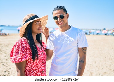 Young latin couple smiling happy and hugging at the beach.