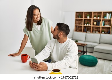 Young latin couple smiling happy using smartphone at home. - Powered by Shutterstock