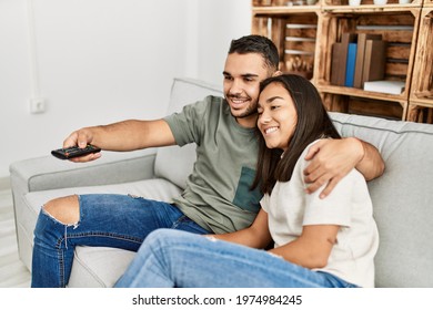 Young Latin Couple Smiling Happy Watching Tv At Home.