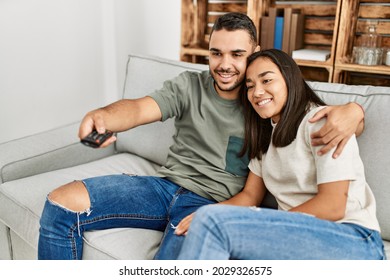 Young Latin Couple Smiling Happy Watching Tv At Home.