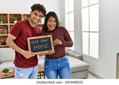 Young Latin Couple Smiling Happy Holding Our First Home Blackboard At House.