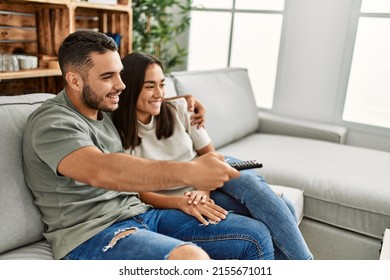 Young Latin Couple Smiling Happy Watching Tv At Home.