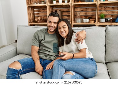 Young Latin Couple Smiling Happy Watching Tv At Home.