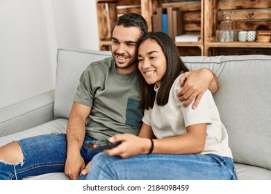 Young Latin Couple Smiling Happy Watching Tv At Home.