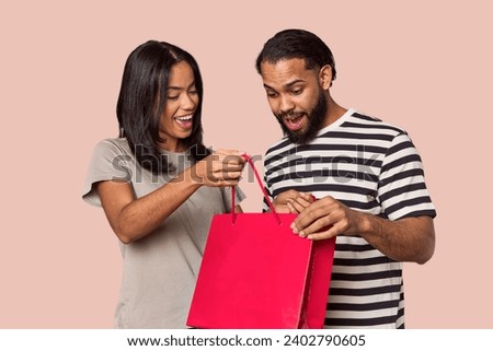 Young Latin couple with Valentine's red shopping bag, studio