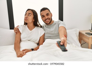 Young Latin Couple Watching Tv Lying On Bed.