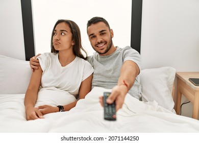 Young Latin Couple Watching Tv Lying On Bed.