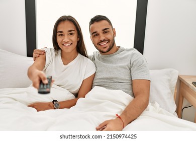 Young Latin Couple Watching Tv Lying On Bed.