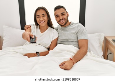 Young Latin Couple Watching Tv Lying On Bed.