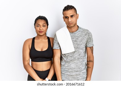 Young Latin Couple Wearing Sportswear Standing Over Isolated Background Skeptic And Nervous, Frowning Upset Because Of Problem. Negative Person. 