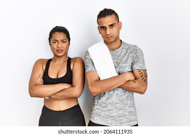 Young Latin Couple Wearing Sportswear Standing Over Isolated Background Skeptic And Nervous, Disapproving Expression On Face With Crossed Arms. Negative Person. 