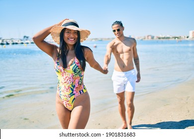 Young latin couple wearing swimwear  smiling happy walking at the beach.