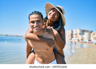 Young Latin Couple Wearing Swimwear  Smiling Happy Walking At The Beach.