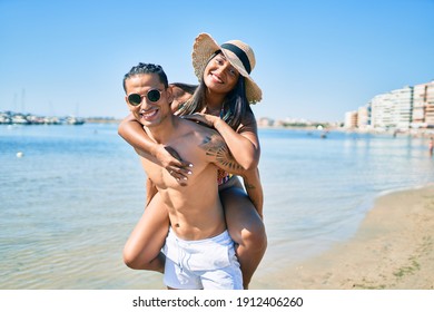 Young latin couple wearing swimwear  smiling happy walking at the beach.