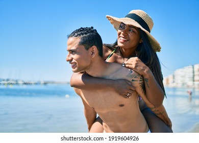 Young Latin Couple Wearing Swimwear  Smiling Happy Walking At The Beach.