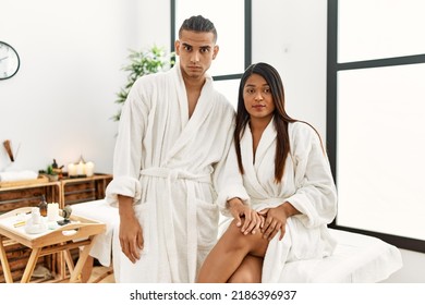 Young Latin Couple Wearing Towel Standing At Beauty Center Skeptic And Nervous, Frowning Upset Because Of Problem. Negative Person. 