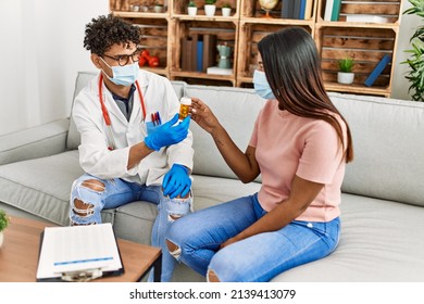 Young Latin Doctor Man Speaking In Medical Consultation Giving Pills To Woman Sitting On The Sofa At The Clinic.