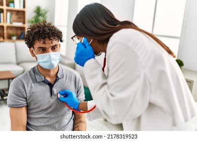 Young Latin Doctor Woman Auscultate Heart Man Using Stethoscope At Medical Room.