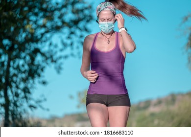 Young latin girl jogging in the park wearing a face mask and a purple tank top - Powered by Shutterstock