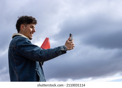 Young Latin Guy Talking By Video Call On The Phone With His Partner Showing Him The Gift For Her. Celebration A Special Day At A Distance.valentine's Day, Birthday, Women's Day, Christmas, Anniversary