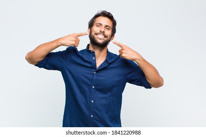 Young Latin Handsome Man Smiling Confidently Pointing To Own Broad Smile, Positive, Relaxed, Satisfied Attitude