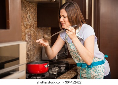 Young Latin Housewife Tasting Some Soup She Just Cooked And Making A Bad Face