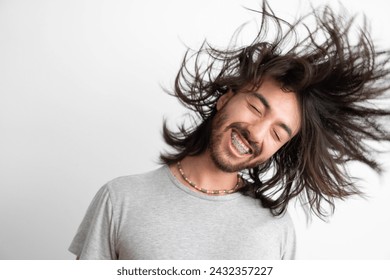 young latin long haired man shaking his long hair while smiling - Powered by Shutterstock