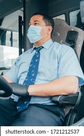 Young Latin Man Bus Driver In Blue Shirt Has Blue Medical Protection Mask And Black  Gloves On Hands.  Bus Driver Wants To Prevent  Infection Of Covid 19. Driver In Mask Looks At Road While Driving.