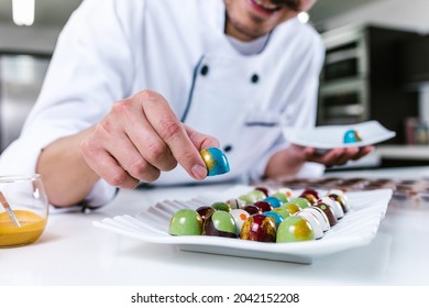 young latin man chocolatier in chef hat standing with mexican chocolates candies on plate in a commercial kitchen in Mexico Latin America