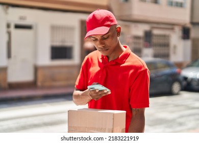 Young Latin Man Delivery Worker Scanning Package Using Smartphone At Street