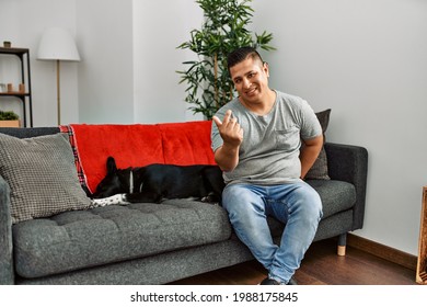 Young Latin Man And Dog Sitting On The Sofa At Home Beckoning Come Here Gesture With Hand Inviting Welcoming Happy And Smiling 