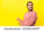 Young latin man isolated on yellow background extending hands to the side for inviting to come