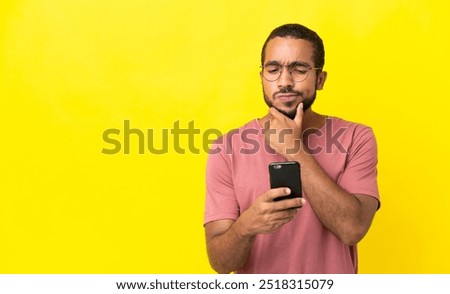 Young latin man isolated on yellow background thinking and sending a message