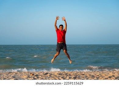 young latin man jumping on the shore of the beach - Shutterstock ID 2259115629