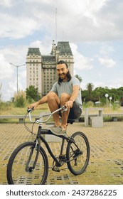 young latin man laughing while riding a bicycle, lifting his feet, testing his balance, playing and having fun.