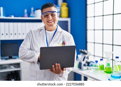 Young latin man scientist smiling confident using laptop at laboratory