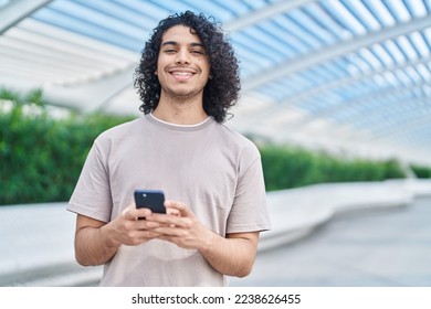 Young latin man smiling confident using smartphone at park - Powered by Shutterstock