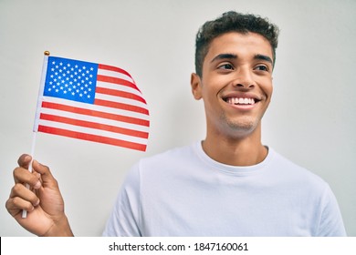 Young Latin Man Smiling Happy Holding American Flag Walking At The City.