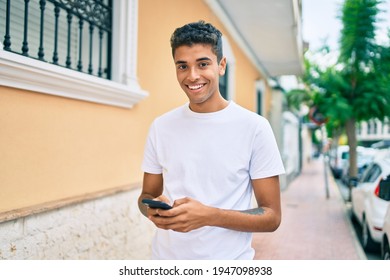 Young latin man smiling happy using smartphone walking at the city. - Powered by Shutterstock