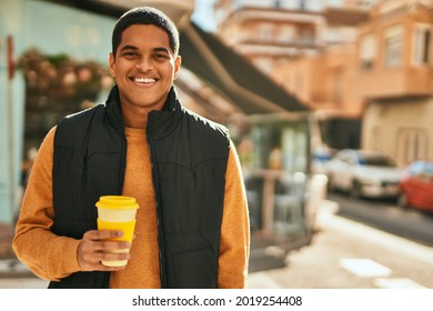 Young latin man smiling happy drinking coffee at the city