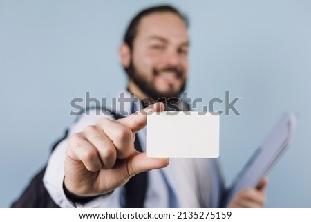 young latin man student university holding a blank card ir identification card on blue background in Mexico Latin America