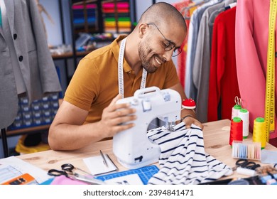 Young latin man tailor smiling confident using sewing machine at atelier - Powered by Shutterstock