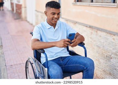 Young latin man using smartphone sitting on wheelchair at street - Powered by Shutterstock