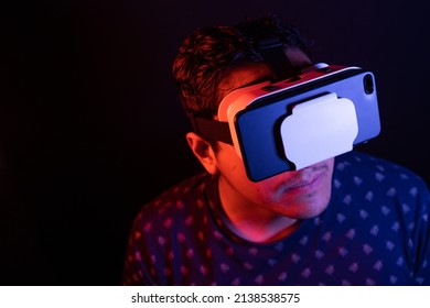 Young Latin Man Using Virtual Reality VR Headset 3D Glasses. Studio Dark Backdrop. Low Key. 