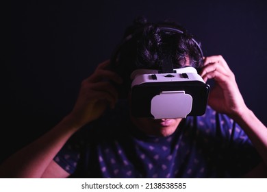 Young Latin Man Using Virtual Reality VR Headset 3D Glasses. Studio Dark Backdrop. Low Key. Copy Space