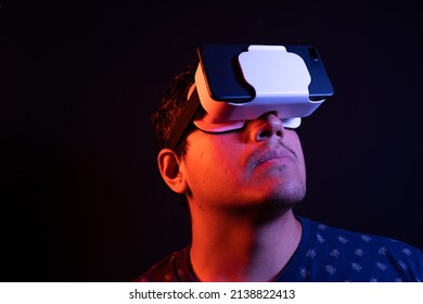 Young Latin Man Using Virtual Reality VR Headset 3D Glasses. Studio Dark Backdrop. Low Key. 