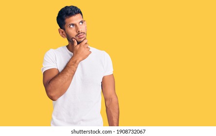 Young latin man wearing casual clothes with hand on chin thinking about question, pensive expression. smiling with thoughtful face. doubt concept.  - Shutterstock ID 1908732067